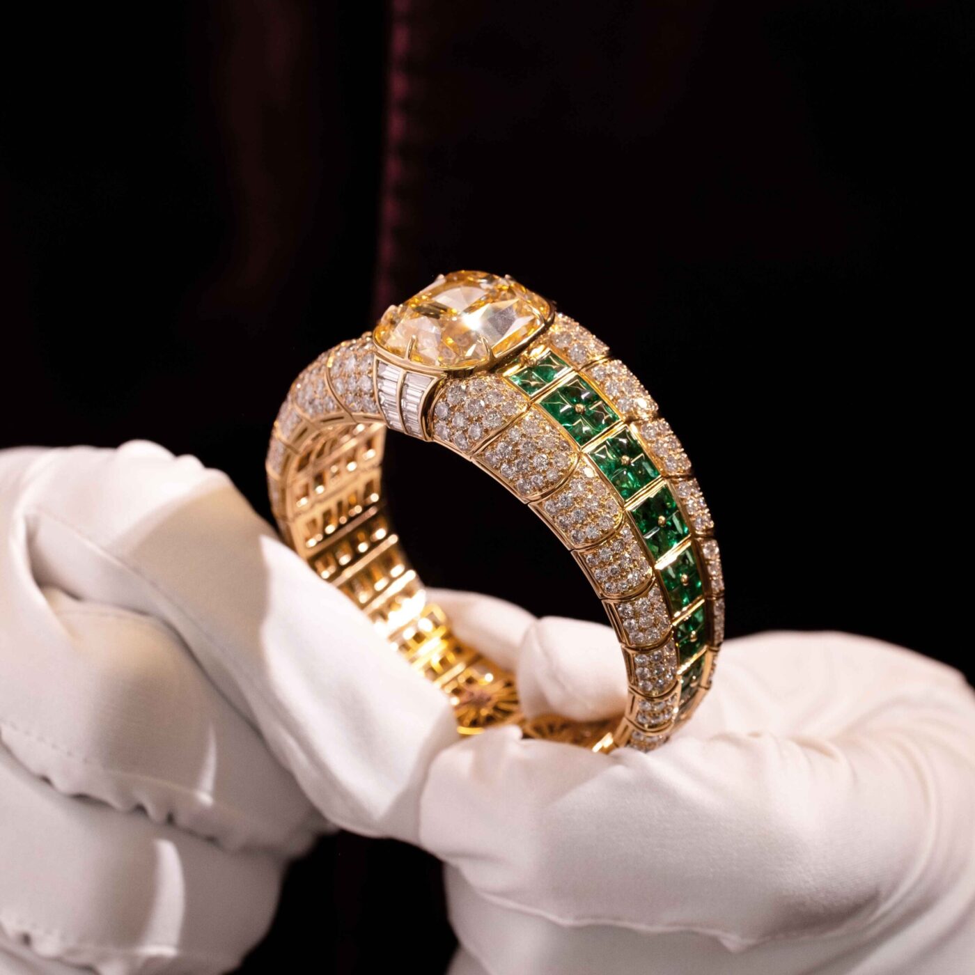 Bulgari Yellow Gold Diamond and Emerald Bangle in hand in white glove